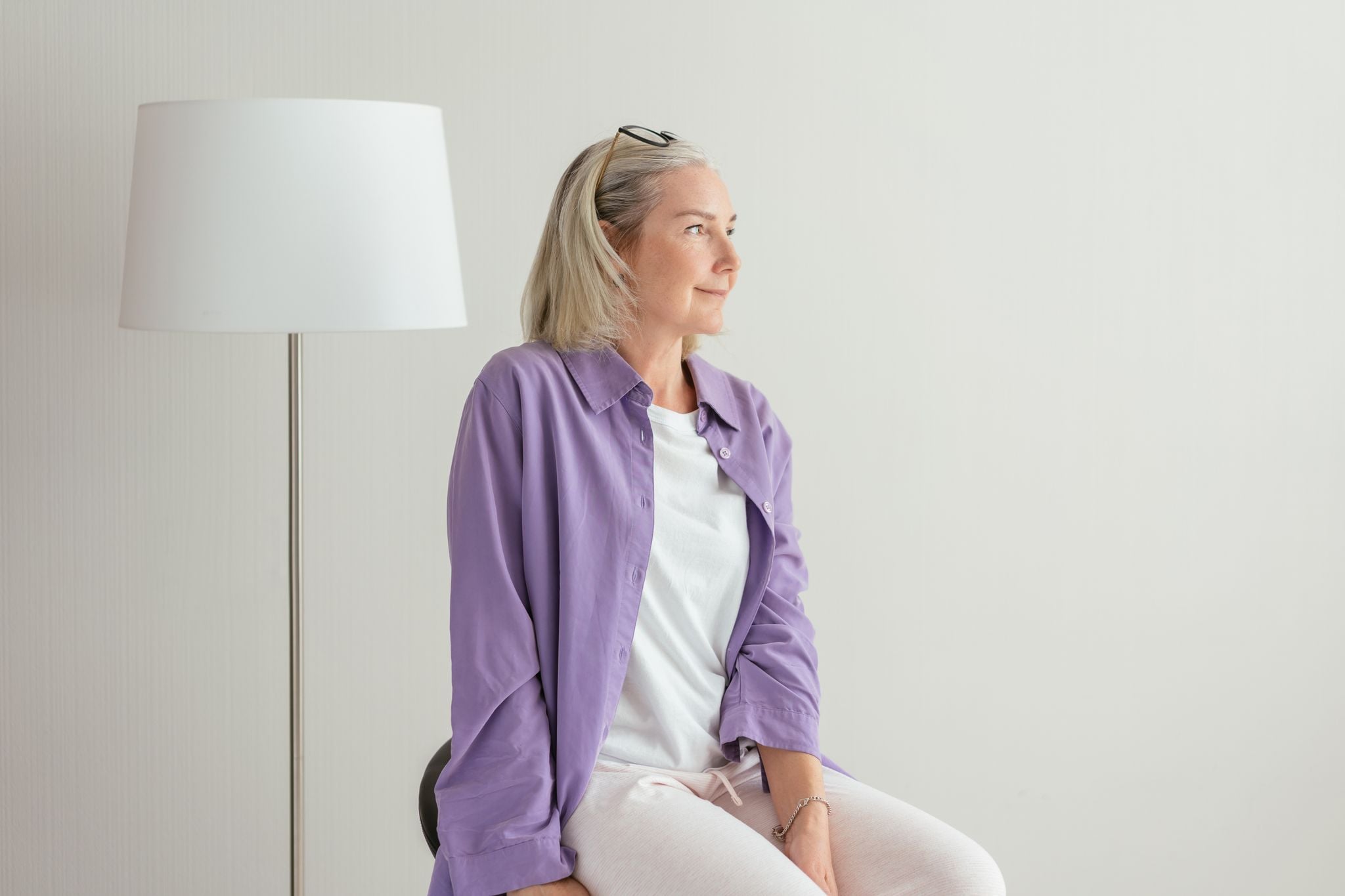 home 9 Portrait of a senior woman in casual attire, sitting indoors with a lamp beside her.